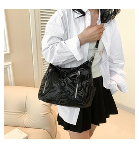 Detail of black marble pattern leather shoulder bag with dual silver zippers on model