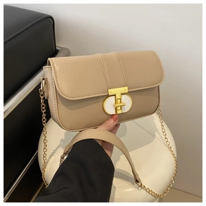 Close-up of beige leather shoulder bag with a gold T-lock and chain strap detail