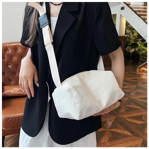 Detail view of a creamy white corduroy pillow bag with adjustable shoulder strap