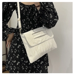 Detail of white PU crossbody bag with marble texture and adjustable strap on a floral dress