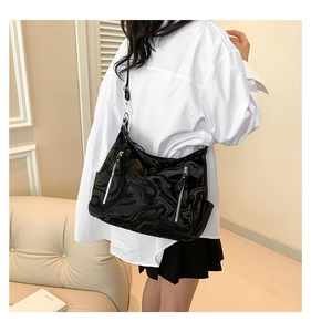 Detail of black glossy shoulder bag with marble texture and silver zipper accents