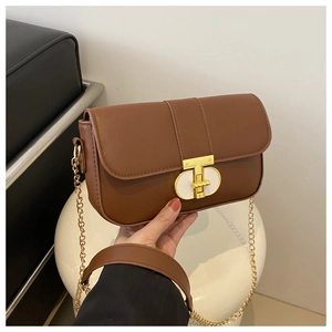 Detail of classic brown PU leather handbag featuring a gold T-shaped metal twist lock
