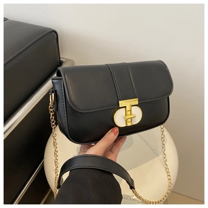 Detail of elegant black square crossbody bag with gold oval clasp and chain strap