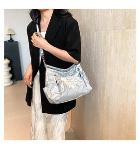 Detail of silver marble textured shoulder bag with zippers on model in black suit