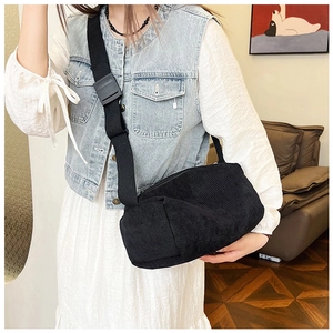 Detail of black corduroy crossbody bag with wide nylon strap shown on a model