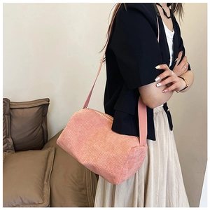 Detail of pink corduroy shoulder bag showing soft ribbed texture and matching strap
