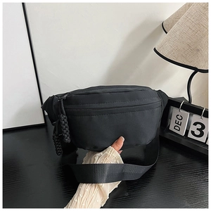 Détail du sac de poitrine minimaliste noir avec nylon texturé et tirettes de zip tressées