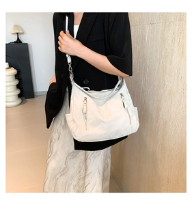 Detail of white marble textured hobo shoulder bag with dual vertical zippers and strap