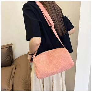 Detail of pink corduroy shoulder bag showing texture and wide strap on model