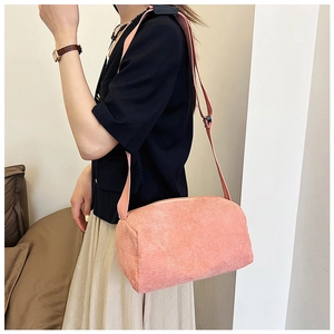 Close-up of pink corduroy cylinder crossbody bag with adjustable strap and top zipper