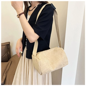 Detail view of large beige corduroy crossbody pillow bag with wide fabric shoulder strap