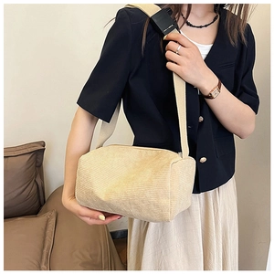 Detail of beige corduroy crossbody bag with wide adjustable strap worn by a model