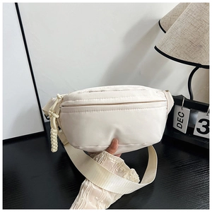Détail du sac de poitrine minimaliste en nylon beige avec tirette de zip tressée