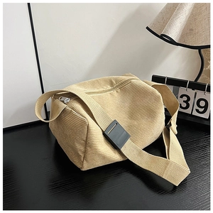 Detail of beige corduroy shoulder bag with vertical texture and adjustable strap on desk