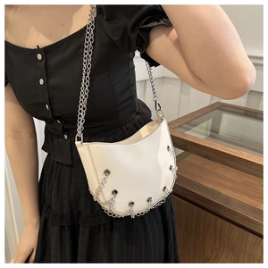 Detail of white crescent shoulder bag with silver chains and eyelet accents