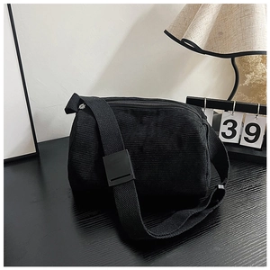 Detail shot of black corduroy messenger bag with textured stripes and adjustable strap