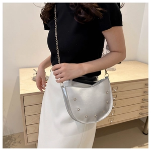 Detail of silver crescent chain bag with metal rivets and sleek golden shoulder strap