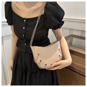 Detail of beige hobo bag with metallic eyelets and silver chain strap on model