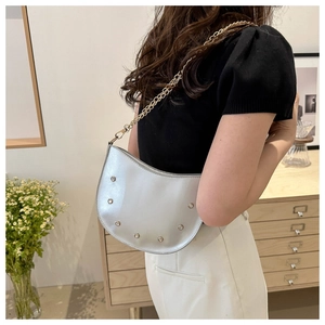Detail of silver crescent bag with stud embellishments and gold chain strap on model