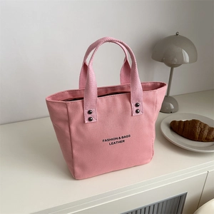 Pink canvas tote bag with metal studs and top handles for commuting and casual wear