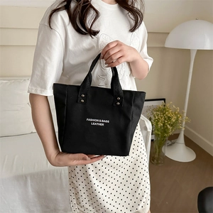 Minimalist black tote bag with white lettering and rivet details for daily commuting