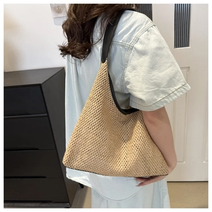 Detailed view of straw woven tote bag with contrast black leather strap for summer beach style