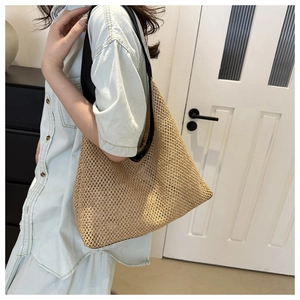Detail of hand-woven straw tote bag with black faux leather strap for summer beach vacation