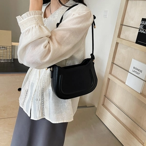 Chic black half-moon underarm bag with U-shaped texture and gold hardware detail