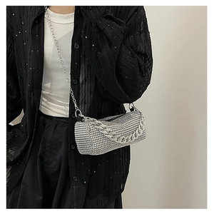 Close-up of silver rhinestone cylinder bag with metallic chain on shoulder