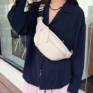 Sac de poitrine minimaliste beige avec fermeture tressée porté par un mannequin