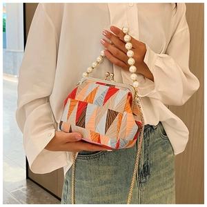 Detail of colorful geometric shell bag with pearl handle and metal clasp closure