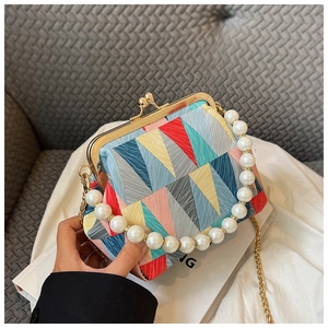 Detail of colorful geometric fabric handbag with pearl handle and metal clasp