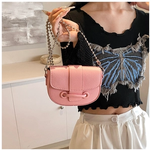 Détail du sac selle en cuir grainé rose avec une chaîne à billes argentées chic