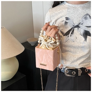 Detail of pink marble box bag with pearl handle, drawstring closure and gold chain strap