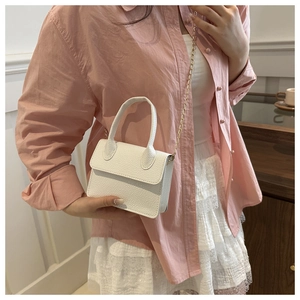 Close-up of a white lychee pattern crossbody bag with golden chain strap on a model