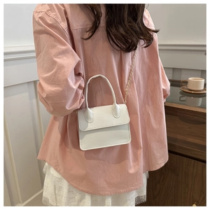 Detail of white litchi pattern mini bag with gold chain strap on a model's side