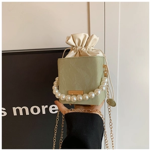 Detail of light green matte box bag featuring pearl handle and gold chain strap