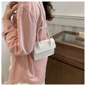 Detail of white mini handbag with lychee leather texture and gold metal chain strap