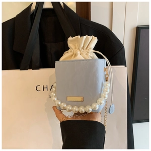 Detail of light blue box bag featuring large pearl handle and golden chain strap