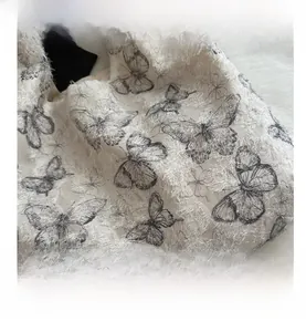 Detail of cream woven jacquard fabric with black butterfly prints and feather texture