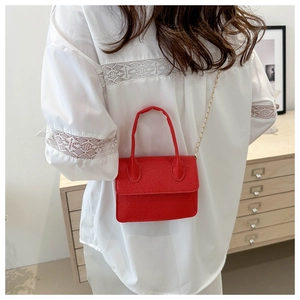 Detail of red litchi texture leather mini crossbody bag with gold chain strap and top handle