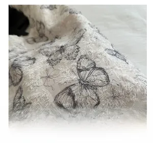 Macro detail of creamy white woven fabric with black butterfly print and fuzzy texture