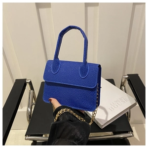 Detail of royal blue pebble leather mini bag on chair with gold chain strap