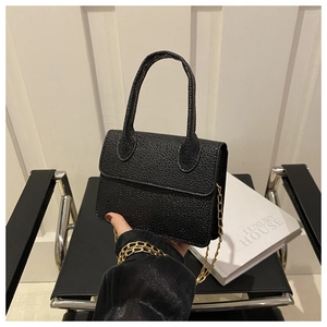 Detail of black mini crossbody bag with pebbled leather texture and gold chain strap