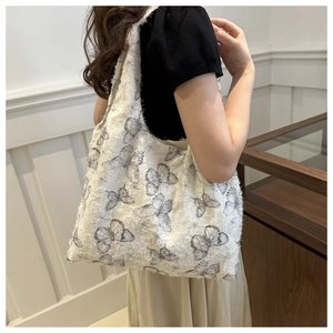 Detail of white tote bag with gray butterfly pattern and frayed fringe edges for women