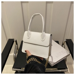Detail of white litchi pattern leather mini bag with gold chain strap and top handle
