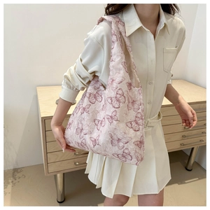 Close-up of pink jacquard shoulder bag with purple butterfly patterns on a model