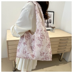 Detailed view of cream jacquard tote bag with purple butterfly print on model's shoulder