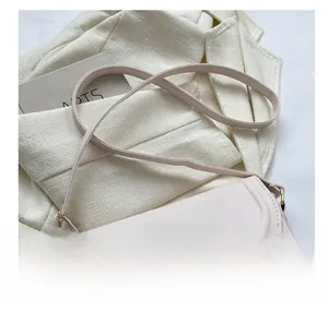 Detail of light beige saddle bag with a round buckle and gold metal ring accent