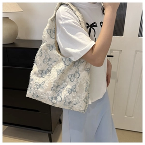 Detail of white butterfly jacquard hobo bag showing fringe edges and blue patterns